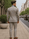 Light blue & beige plaid suit with a fitted blazer, vest, and matching trousers. Tailored with gold buttons, structured shoulders, and a narrow waist. Symmetrical pattern.