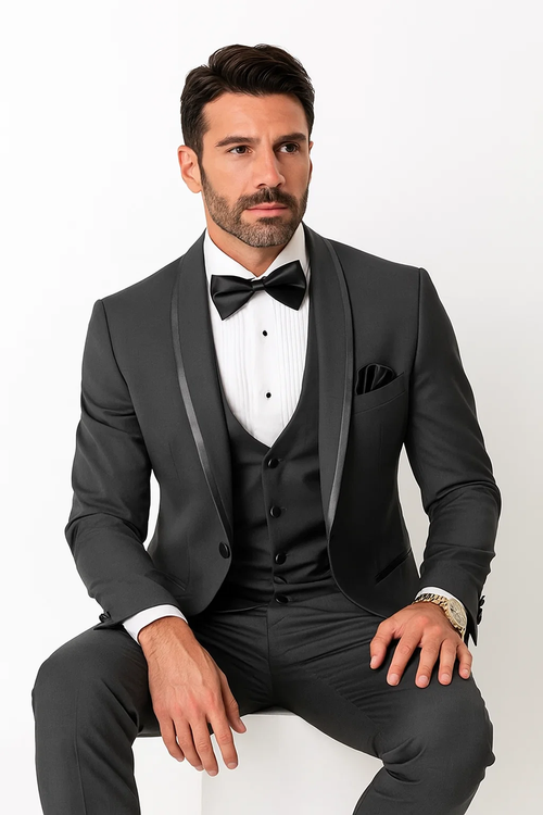 Men's charcoal satin shawl tuxedo suit: slim-fit, single-breasted jacket, satin lapels, matching vest. Smooth, glossy fabric. Paired with a striped white shirt, black bow tie, pocket square, and tailored pants. Formal and elegant.