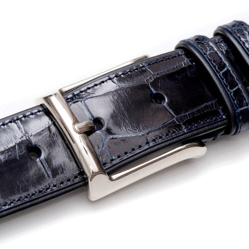 Dark blue alligator belt by Mezlan. Glossy finish, silver buckle, and matching stitching. Features evenly spaced adjustment holes.