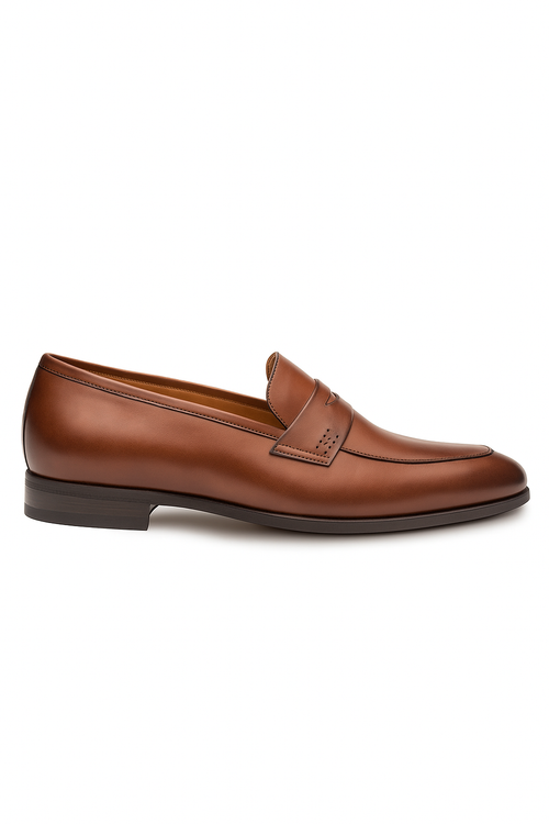 Mezlan Fabrizi penny loafer in cognac calfskin. Smooth, rounded toe with decorative strap and perforated details. Dark brown sole, low stacked heel. Sleek and stylish.