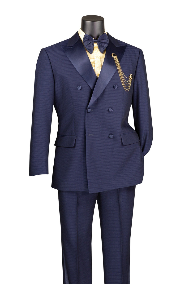 Navy double-breasted tuxedo with satin peak lapel. Subtle textured fabric. Matching trousers. Gold chain detail on the left pocket. Classic and elegant.