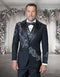 The Statement mens 3 piece modern fit tuxedo features a black jacket with floral applique detailing on one side, complemented by a black satin shawl collar. The ensemble includes a matching vest with a similar floral pattern and black pants, all in a sleek design.