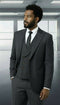 Statement men's 3 piece modern fit suit features a peak lapel design, made from 100% wool in a dark gray shade. The coat has a single-button closure, with a tailored fit and structured shoulders. The waistcoat includes five buttons, showcasing a sleek, refined look.