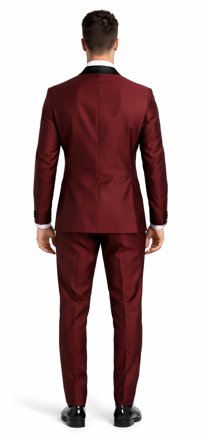 Elegant burgundy three-piece tuxedo with shawl lapel. Smooth, tailored fit in deep burgundy. Sleek back with single vent. Matching trousers. Structured, form-fitting silhouette.