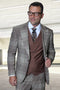 Men's designer suit: Italian wool, brown houndstooth plaid. One-button peak lapel jacket & double-breasted vest. Brown, cream, black accents. Structured shoulders, tailored fit. Textured plaid pattern.
