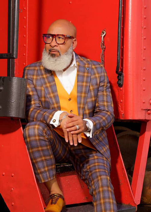 Men's Stacy Adams suit: grey/gold plaid jacket & slim-fit pants. Includes orange vest, white dress shirt, and a watch. Bold windowpane pattern.
