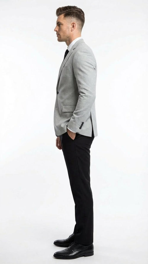 Men's light grey slim-fit blazer with structured fit, two pockets, and single-button closure. Styled with black slim-fit pants and black shoes.
