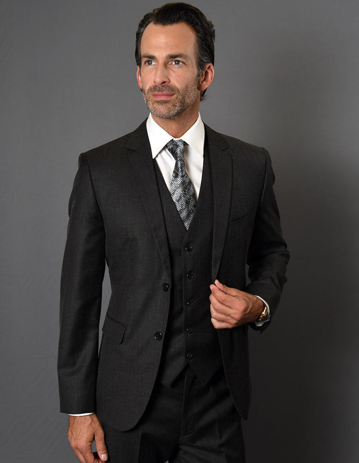 Men's slim fit, 2-button vested suit in black textured fabric. Includes jacket, matching vest, and tapered trousers. Modern fit, dark fabric.
