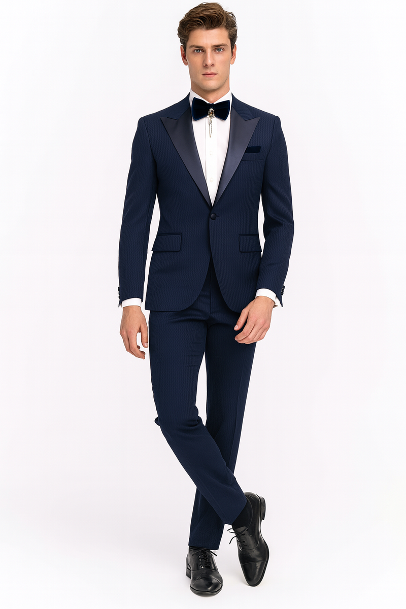 Navy blue tuxedo with satin peak lapel. Two-piece suit features a fitted blazer, tailored trousers, subtle patterned texture, and a navy bow tie. A cohesive formal look.
