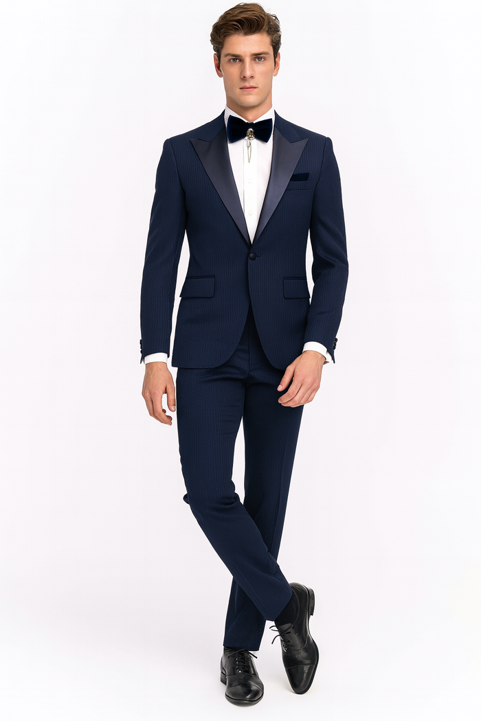 Navy blue tuxedo with satin peak lapel. Two-piece suit features a fitted blazer, tailored trousers, subtle patterned texture, and a navy bow tie. A cohesive formal look.
