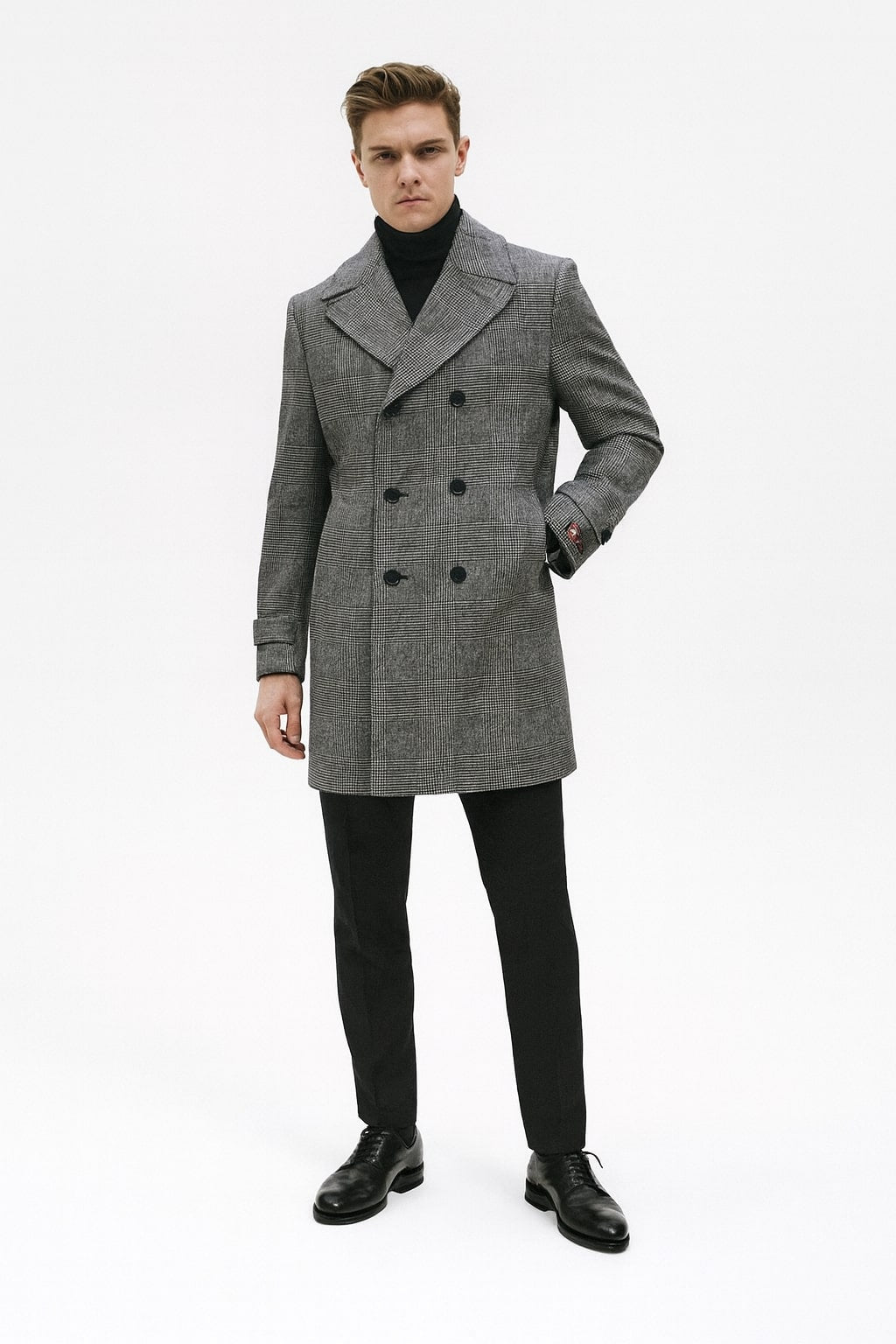 Men's grey plaid double-breasted overcoat. Black faux fur collar, notched lapel, two rows of buttons, and a slightly tailored fit.
