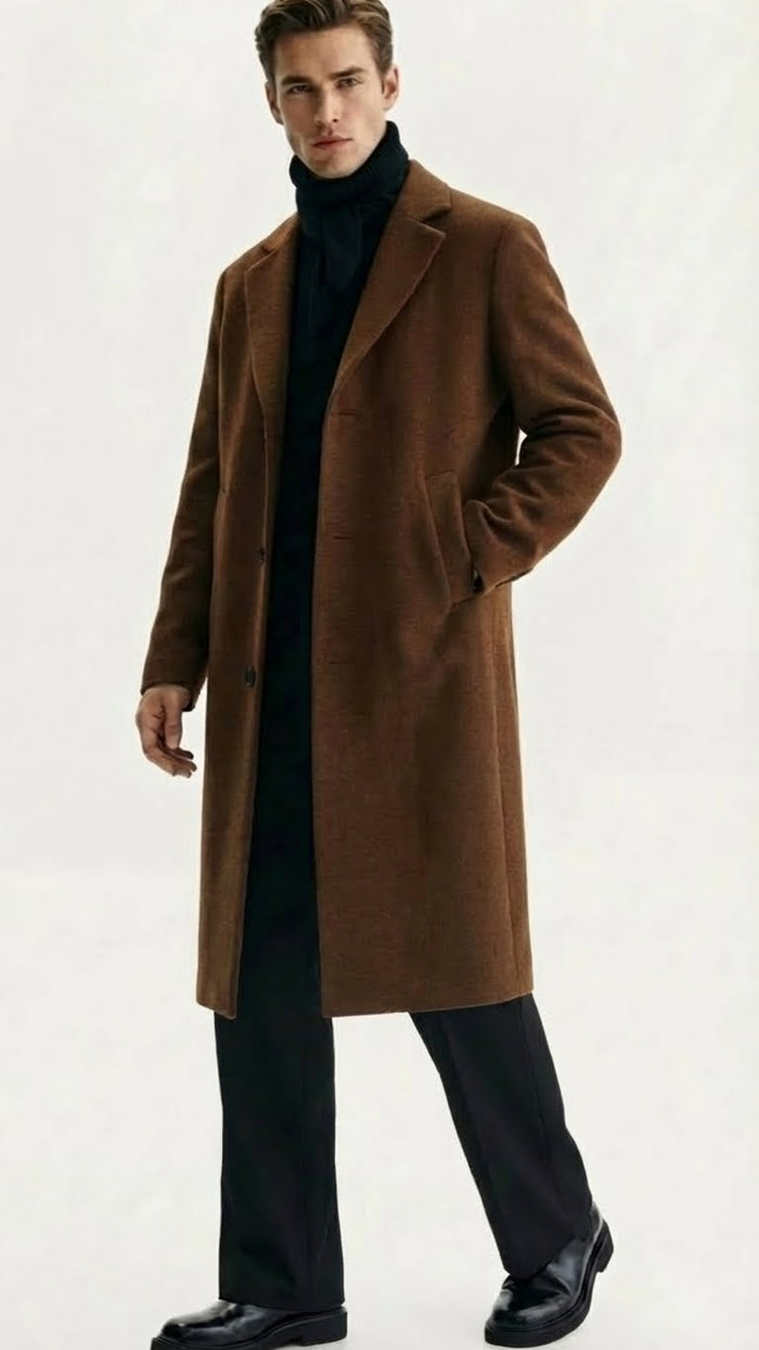 Men's brown wool overcoat with straight silhouette, notch lapel, button closure, and two pockets. Soft, textured fabric. Worn over black turtleneck. Classic style.
