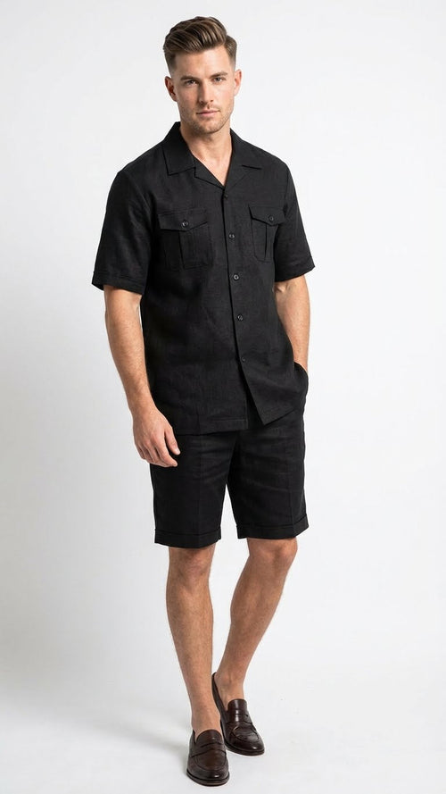The men's black walking suit by Alberto Nardoni features a short-sleeved button-up shirt with a collar and two front pockets. The matching shorts are knee-length, made from a lightweight fabric that appears slightly textured. Both pieces are solid black.