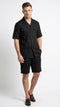The men's black walking suit by Alberto Nardoni features a short-sleeved button-up shirt with a collar and two front pockets. The matching shorts are knee-length, made from a lightweight fabric that appears slightly textured. Both pieces are solid black.