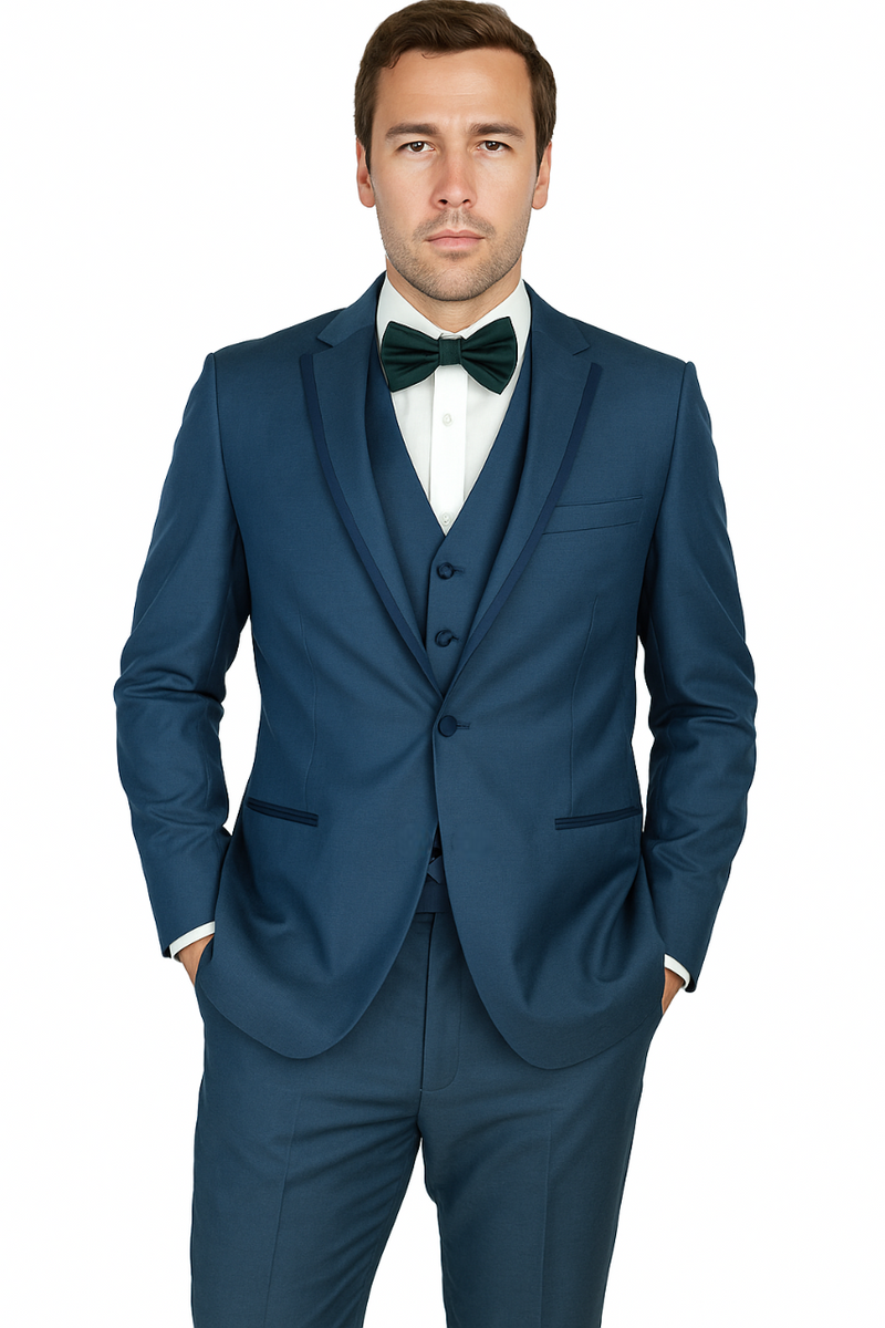 Dark blue Oscar tuxedo: structured, single-breasted. Features sharp lapels, fitted silhouette, and matching waistcoat. White shirt, green bow tie complete the look.
