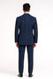 Royal blue double-breasted suit with white pinstripes. Fitted jacket, structured silhouette, notched lapel, and long sleeves. Matching straight-leg trousers. Tailored fit emphasized from rear.
