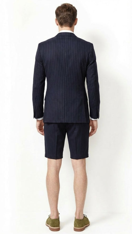Men’s dark navy blue pinstripe summer business suit featuring a tailored blazer and matching shorts. The blazer is structured with a slim fit and elongated sleeves.