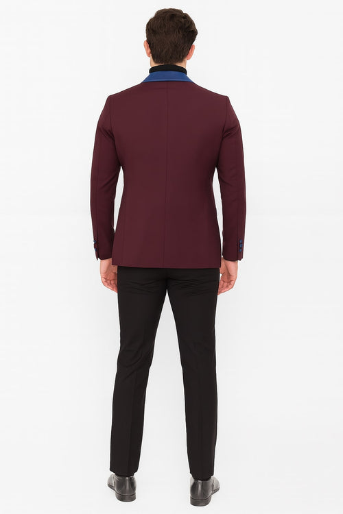 Men's burgundy tuxedo jacket: tailored, fitted silhouette. Blue satin collar contrasts the deep burgundy. Structured back, clean design. Long sleeves with matching buttons, elegant and refined.
