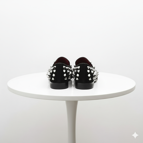 Men's black loafers with silver spikes on the upper. Smooth, glossy finish and burgundy interior. Flat, slightly raised soles. Bold, studded exterior design.

