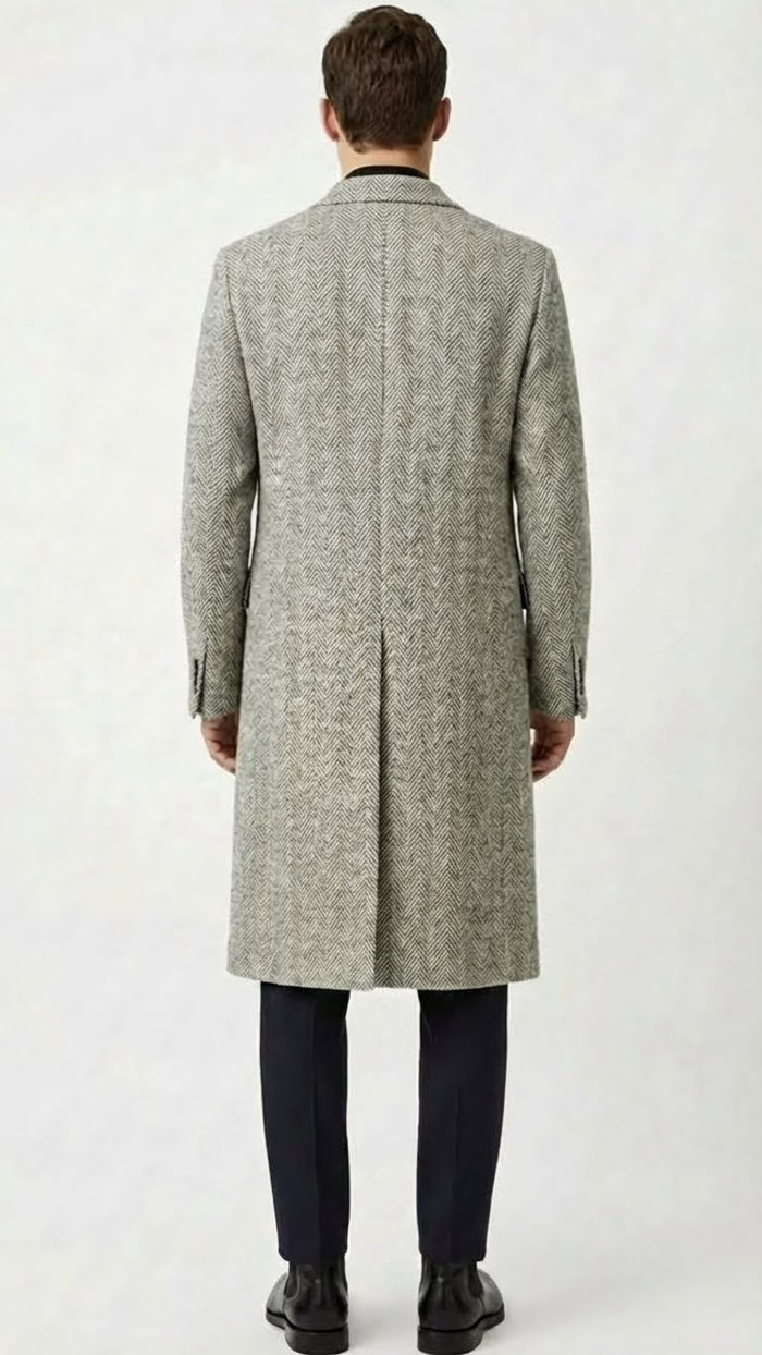 Men's grey herringbone overcoat: tailored fit, straight silhouette, mid-length. Textured fabric with grey herringbone pattern. Notched collar, buttoned cuffs, single back vent. Classic, clean design.
