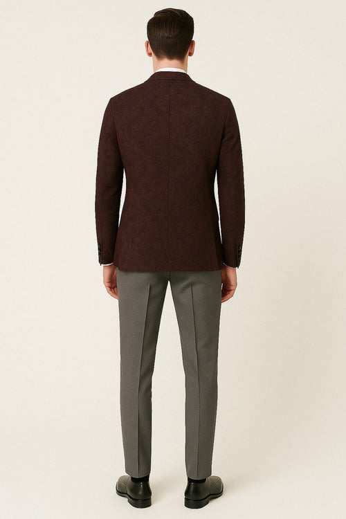 Burgundy & black paisley tuxedo blazer. Fitted, notch lapel, single vent. Paisley pattern in varying shades. Long sleeves with buttoned cuffs. Structured look. Interior lining not visible.
