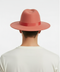 Men's coral pink wool felt fedora hat with a wide brim and smooth crown. Features a red ribbon band.
