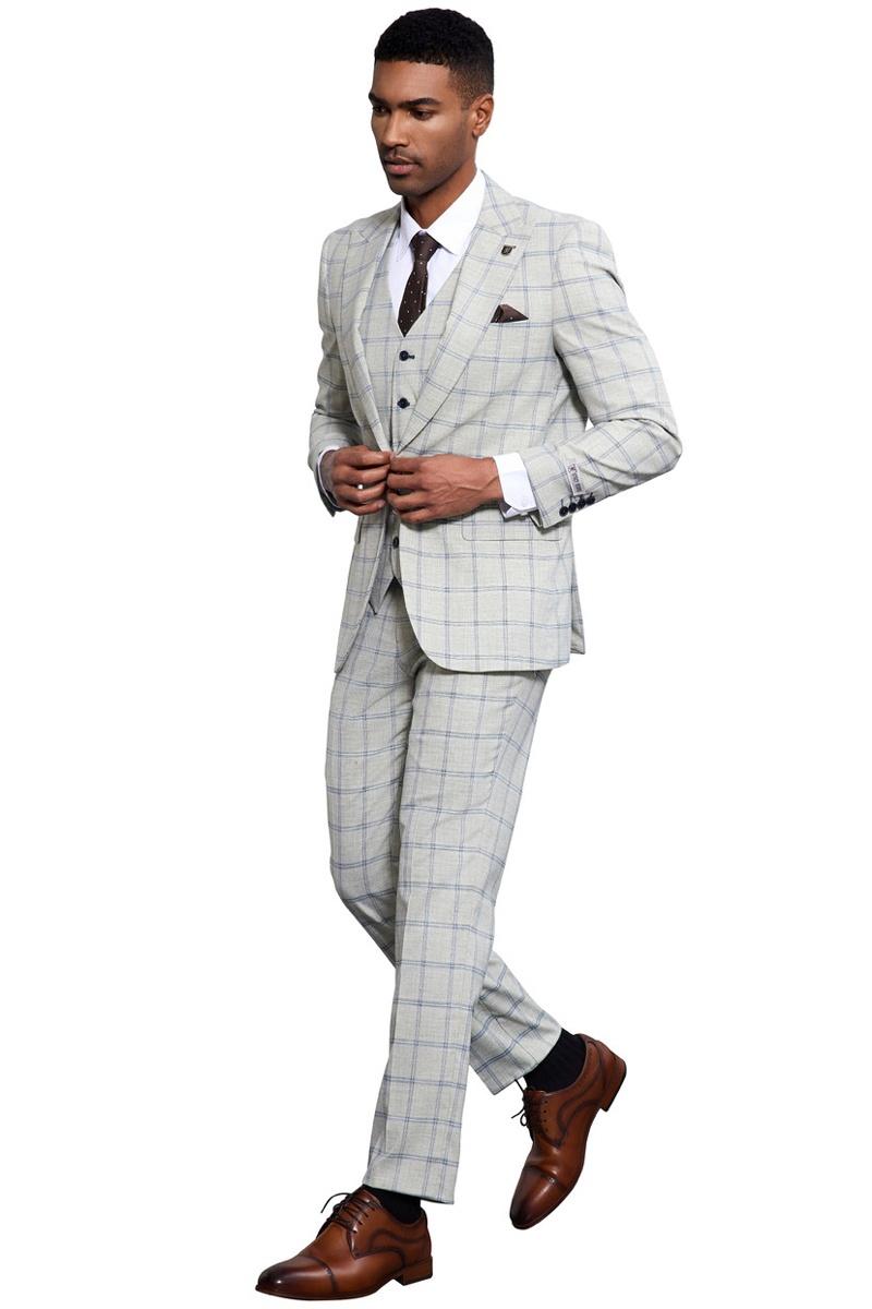 Stacy Adams men's grey-blue windowpane plaid suit. Tailored fit with peak lapel, single-button, and vest. Features slim-fit trousers. Paired with brown shoes, white shirt, and brown polka dot tie.
