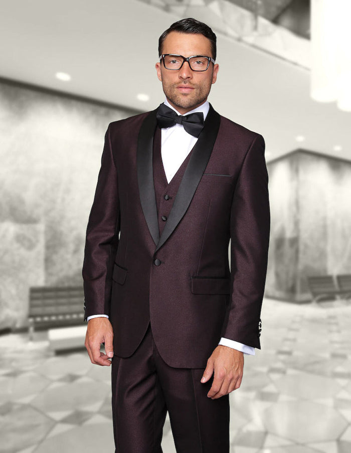 Burgundy one-button tuxedo with shiny fabric and contrasting shawl lapel. Includes a built-in vest, classic fit. Worn with white shirt & black bow tie. Tailored silhouette.
