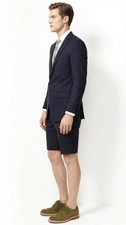 Men’s dark navy blue pinstripe suit consisting of a fitted blazer with a single button and matching shorts that end above the knee, crafted from a smooth fabric.