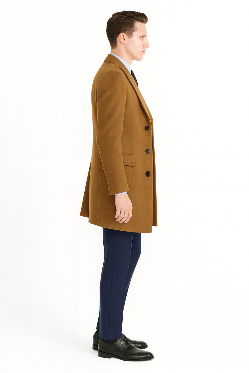 Men's camel brown wool overcoat: long, double-breasted, notched lapels, and three buttons. Features side pockets and a smooth finish. Tailored silhouette, reaching mid-thigh. Styled with navy trousers for a clean, professional look.
