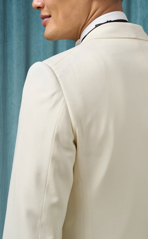 Ivory men's dinner jacket: smooth, tailored fit with structured shoulders. Cream-colored, lightweight fabric for a clean look. Single-breasted design with subtle lapels, ideal for formal events.
