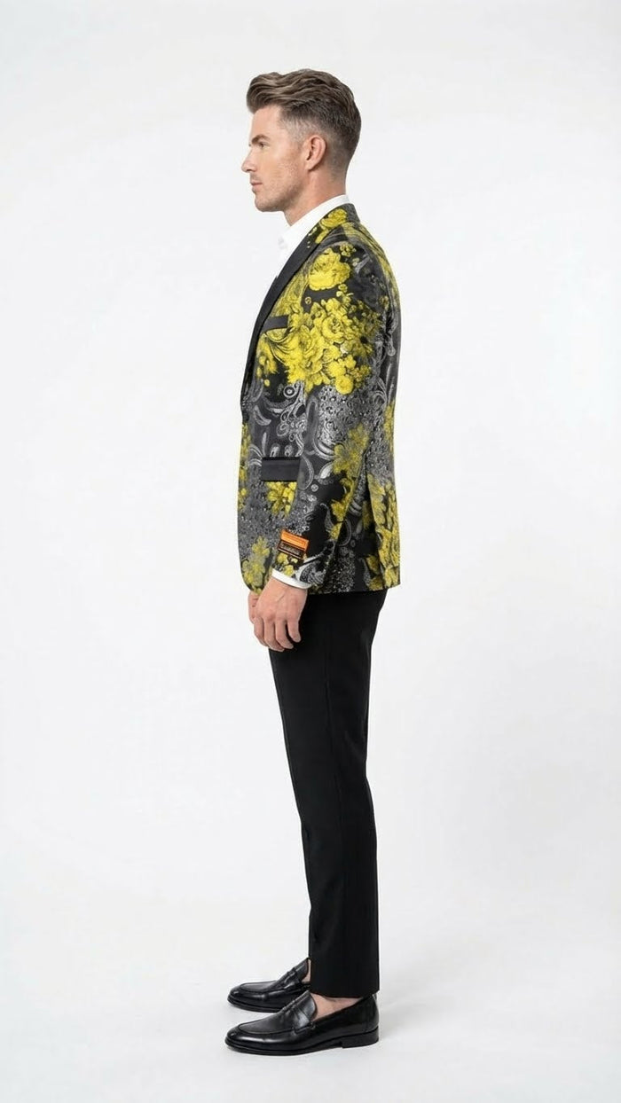 Yellow tuxedo with black & gold floral blazer. Fitted, smooth fabric, black lapel, and pocket detail. Floral pattern prominent. Paired with black trousers & shoes. Single-breasted.
