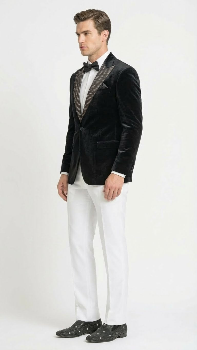 Men's black velvet tuxedo blazer: fitted silhouette, studded lapel, smooth black fabric. Contrasting patterned lapel. Structured and refined appearance.
