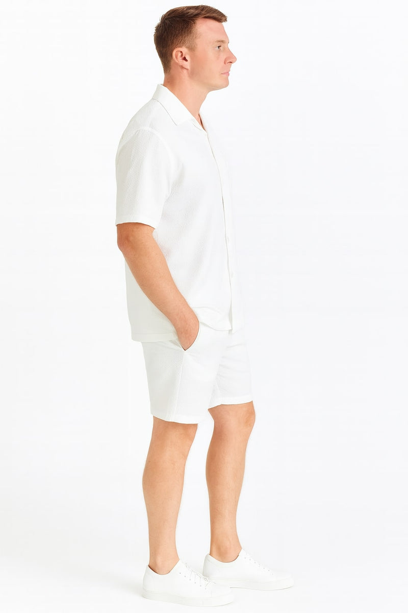 White seersucker short set: short-sleeve collared shirt and relaxed-fit shorts. Lightweight, perfect for summer. Slightly textured fabric.
