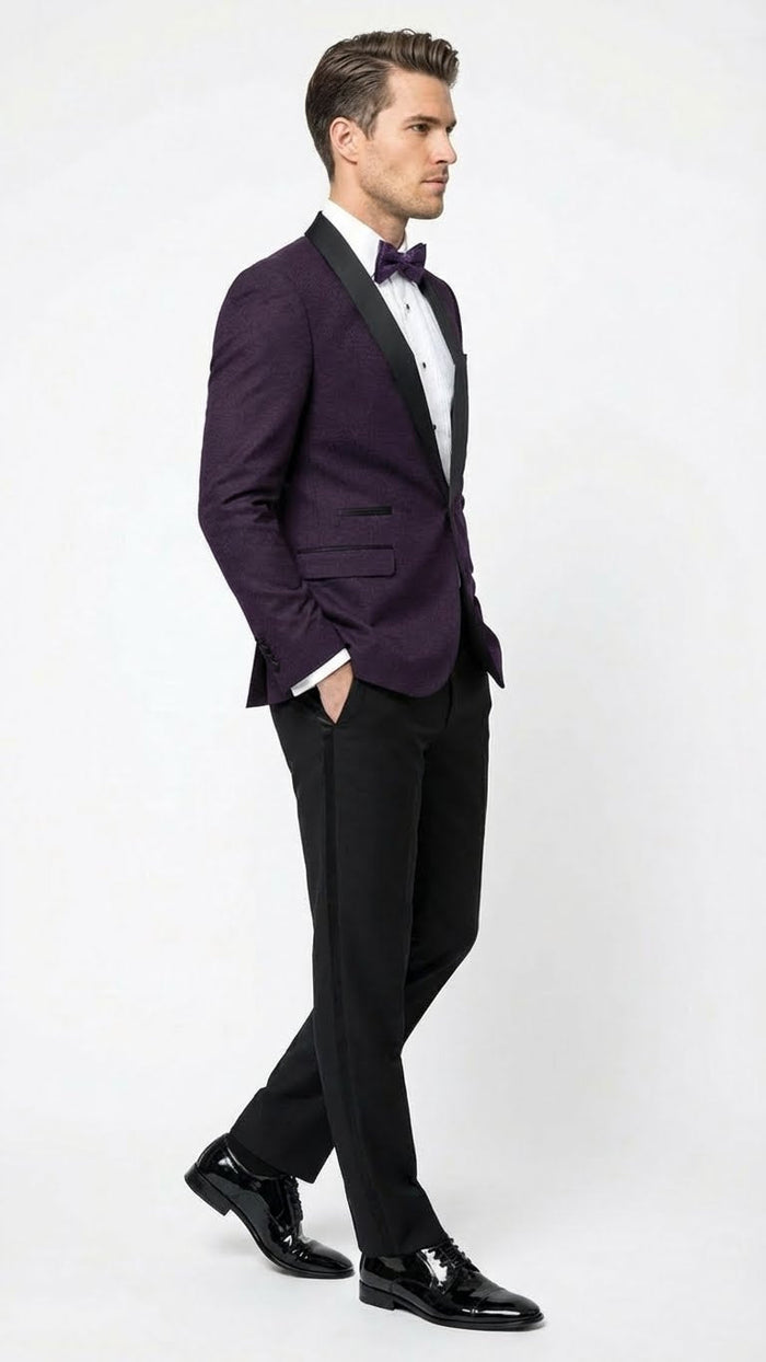 Men's eggplant purple tuxedo blazer. Fitted silhouette, satin lapel, single-breasted. Features two front pockets and textured fabric. Stylish formalwear.

