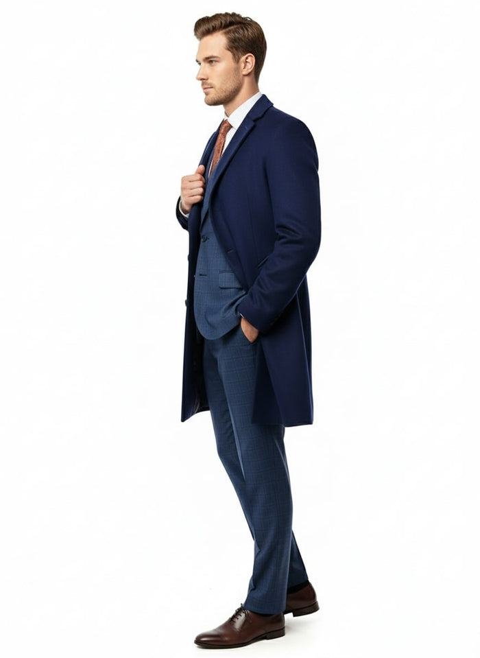 Cobalt blue men's car coat. Wool and cashmere blend, straight silhouette, notched lapels, single-button closure. Mid-length, smooth texture, tailored fit. Worn over suit and shirt.
