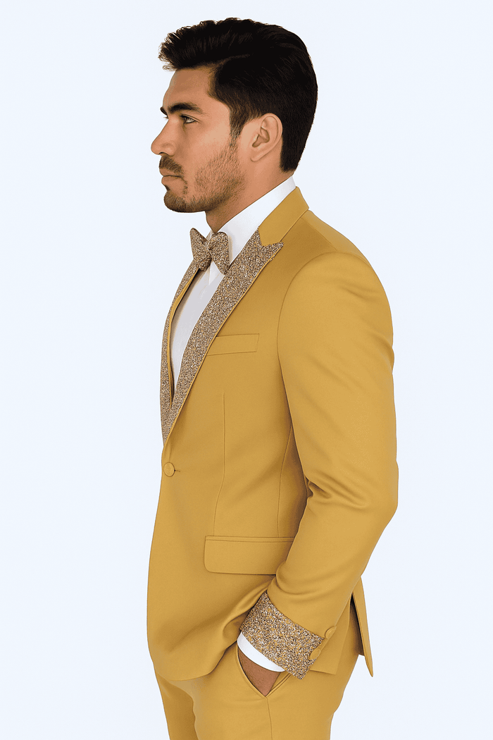 Men's champagne gold prom tuxedo: fitted blazer with sparkling lapel, matching trousers, vest. Gold color, white shirt, textured gold bow tie. Sleek silhouette, structured shoulders, single-button closure, streamlined pockets. Jacket lining visible at cuffs.
