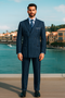 Royal blue men's double-breasted suit with pinstripes. Wide lapels, straight silhouette, and matching tailored trousers. Fine vertical pinstripes in contrasting shades throughout.
