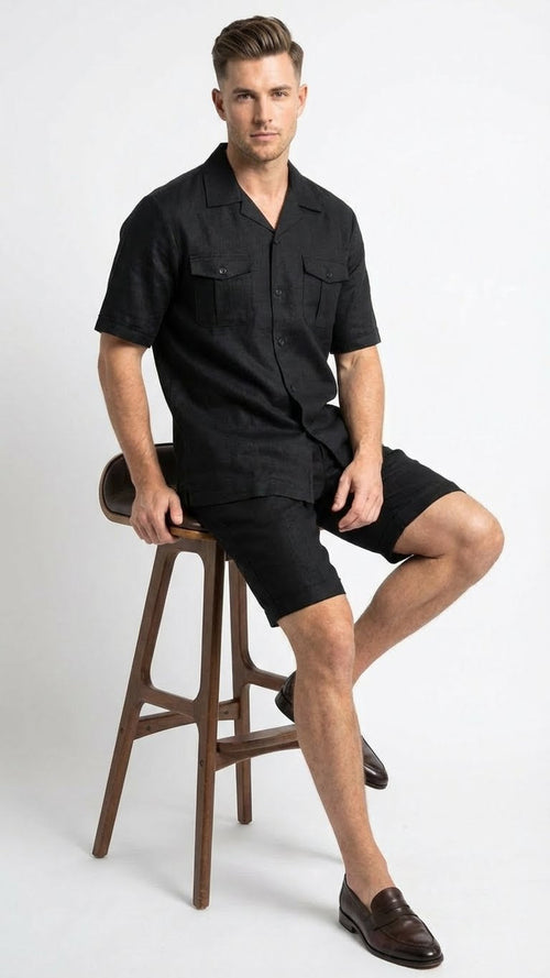The men's black walking suit by Alberto Nardoni consists of a short-sleeved button-up shirt and knee-length shorts, both in a solid black color. The shirt features two chest pockets and a relaxed fit, while the shorts complement the shirt with a matching design.