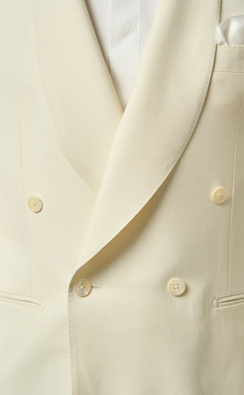 Ivory men's dinner jacket. Double-breasted with creamy hue, two front buttons, peak lapels. Smooth fabric, left-side pocket.
