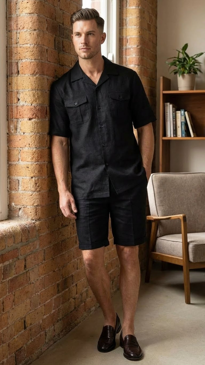 Men's black walking suit featuring a short-sleeve button-up shirt and matching shorts. The shirt has a relaxed fit, with two chest pockets, and the shorts are knee-length, made from a smooth material. The entire outfit is uniform in solid black color.