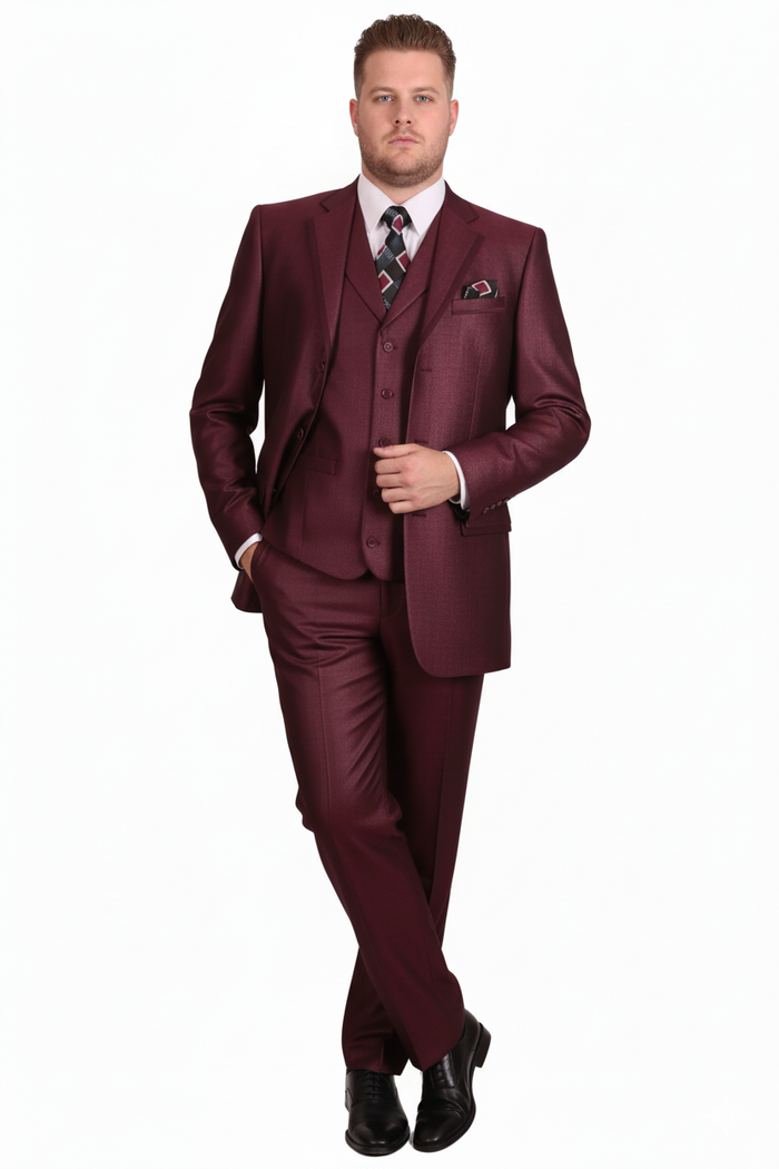 Burgundy three-piece suit: fitted single-breasted jacket, matching trousers, and waistcoat. Smooth, shiny fabric. Includes notch lapels, pocket square, and button-down waistcoat. Paired with a patterned tie and black shoes.
