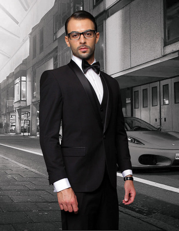 Men's black wool tuxedo. Modern fit, one-button, shawl lapel. Three-piece vested design. Includes white dress shirt and bow tie. Tailored structure.

