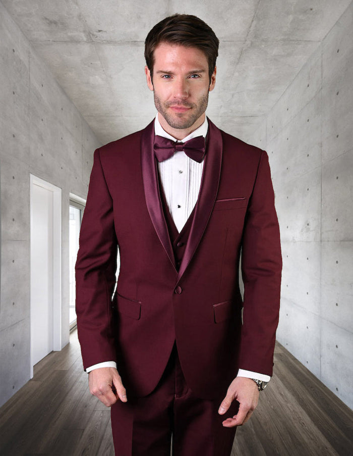 Burgundy men's wool tuxedo: modern fit, one-button, vested. Tailored jacket with shawl collar, matching vest, flat-front trousers. Deep burgundy, subtle sheen. Includes shirt & bow tie.
