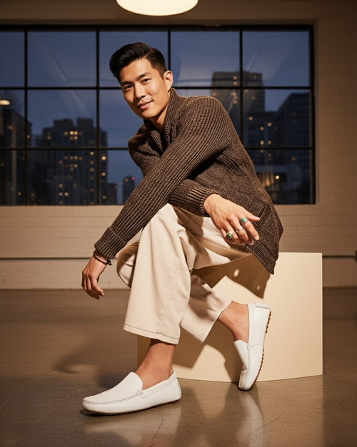 Classic white leather loafers with rounded toe and slip-on design. Visible stitching and rubber outsole with tread pattern for grip.
