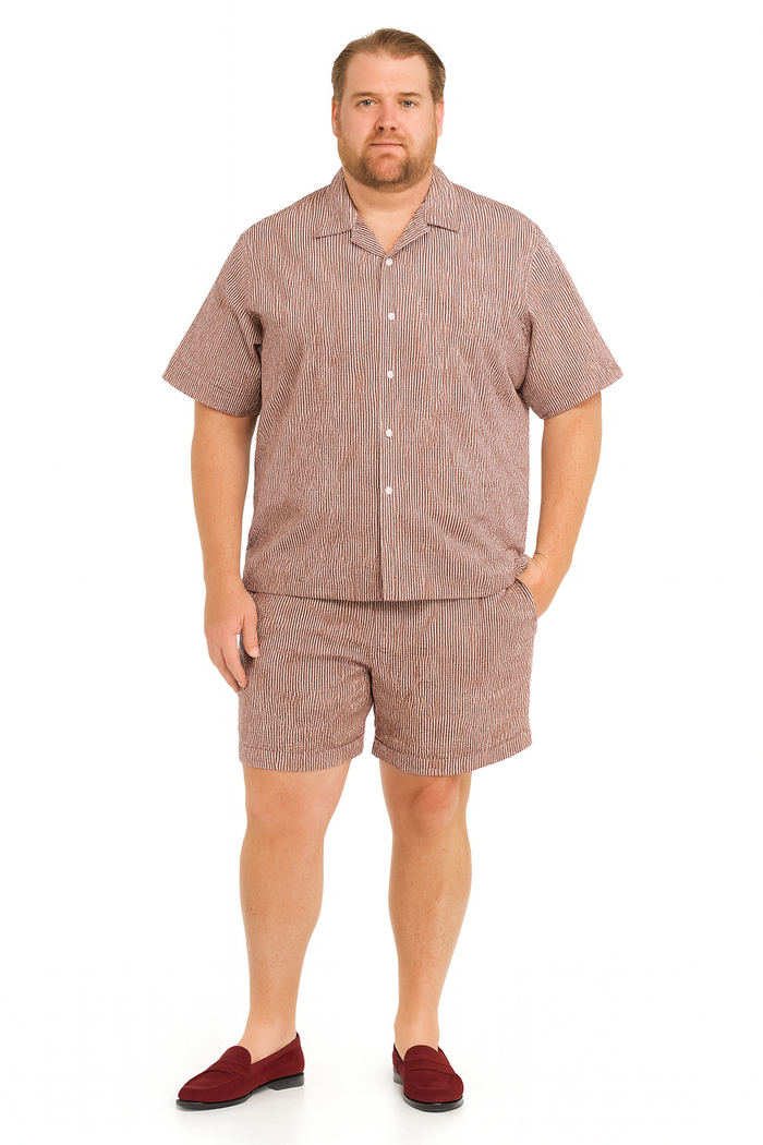 Men's burgundy seersucker short set: short-sleeved button-up shirt with notched collar & matching knee-length shorts. Striped burgundy & white pattern. Loose fit, lightweight fabric.
