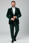 Dark green velvet tuxedo jacket for men. Structured silhouette, single-button closure, peak lapels. Plush velvet fabric. Chest pocket, tailored fit, buttoned cuffs. Rich, dark green.
