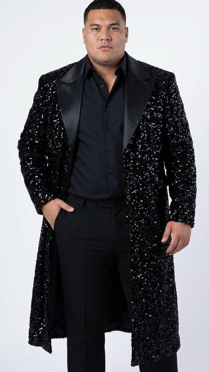 Men's black sequin long coat with satin lapel. Fully lined, covered in reflective sequins. Tailored silhouette, long sleeves, open front. Intricately textured, distinctive appearance.
