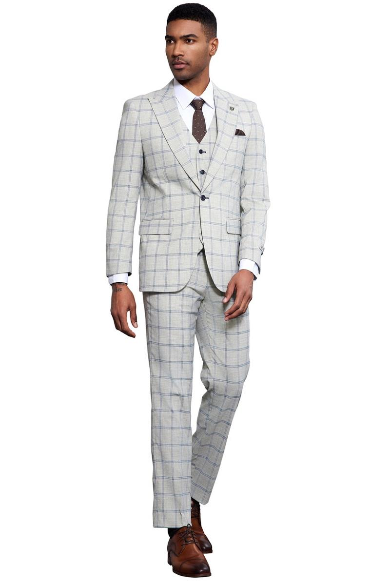 Men's Stacy Adams grey-blue windowpane plaid suit. Tailored fit, single-button, peak lapel, vested. Features a light grey fabric with a blue check pattern. Slim trousers, paired with brown dress shoes.
