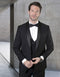 Black wool tuxedo with shawl collar and one-button closure. Includes a matching double-breasted vest with satin details. Tailored fit for a sophisticated look.
